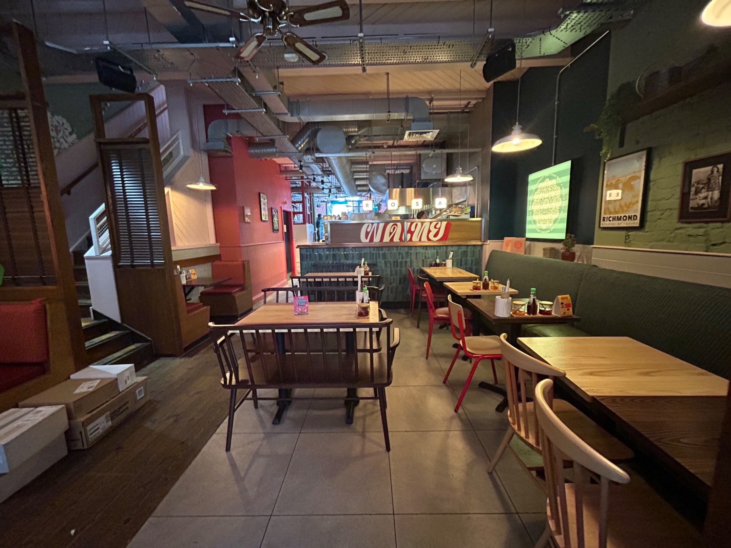 From end of divider, facing right. Half booths along right wall. Booths ahead. Path along left. Open kitchen counter behind seating.