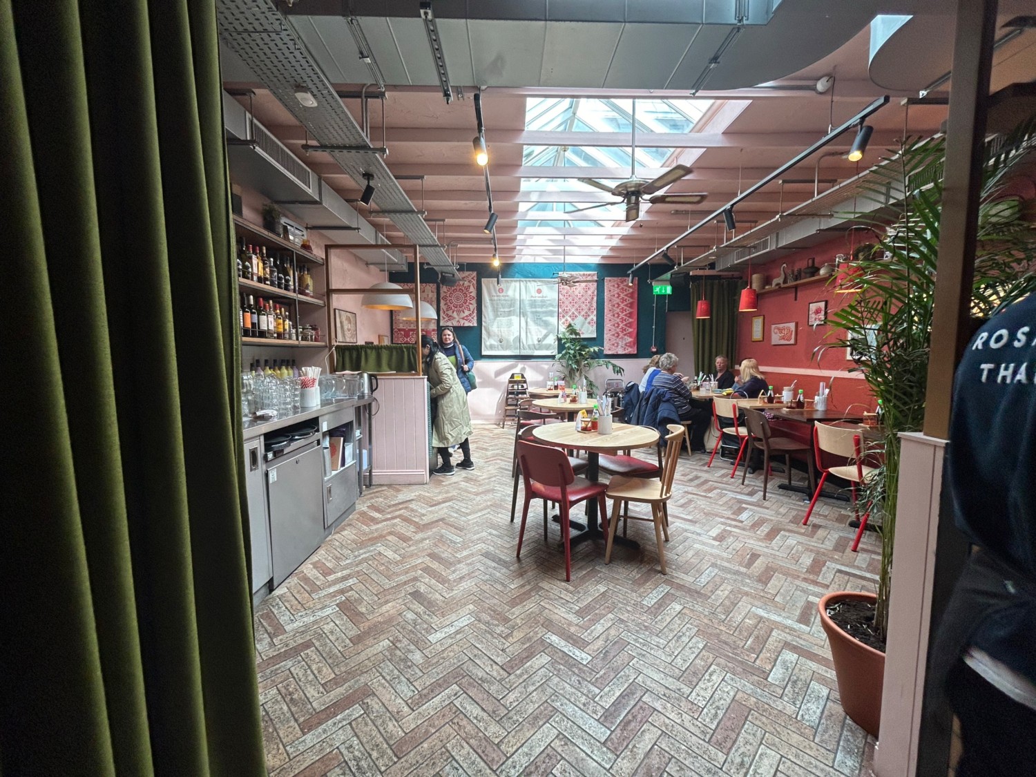 From top of steps, facing straight. Archway ahead with green curtain, push from right to open. Path on left and right. Tables and chairs in middle.