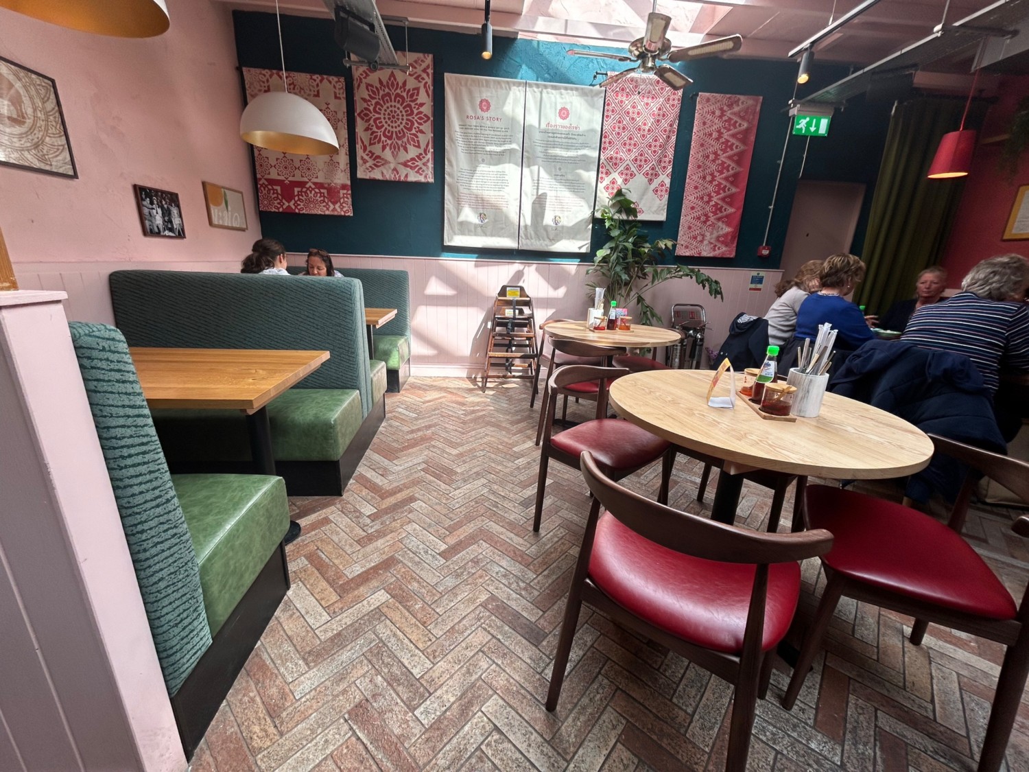 From start of booths, facing straight. Booths along left wall. Tables and chairs along right. Path in middle.