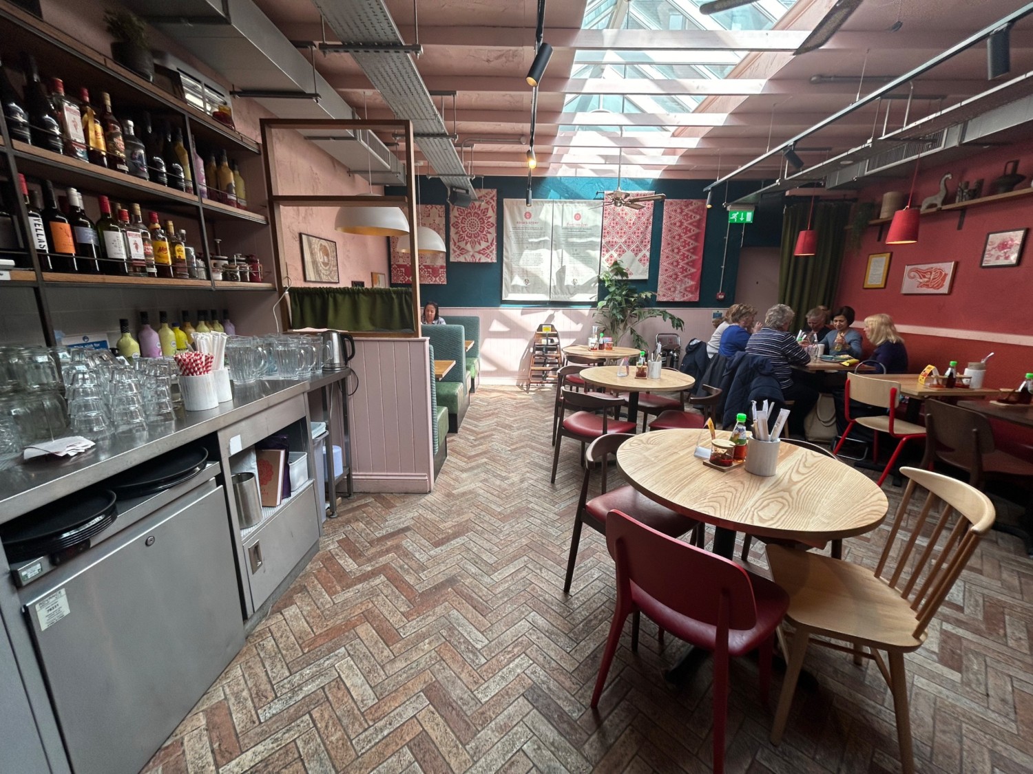 From start of left pathway, facing straight. Bar area on left, then booths along left wall. Tables and chairs on right. Path down middle.