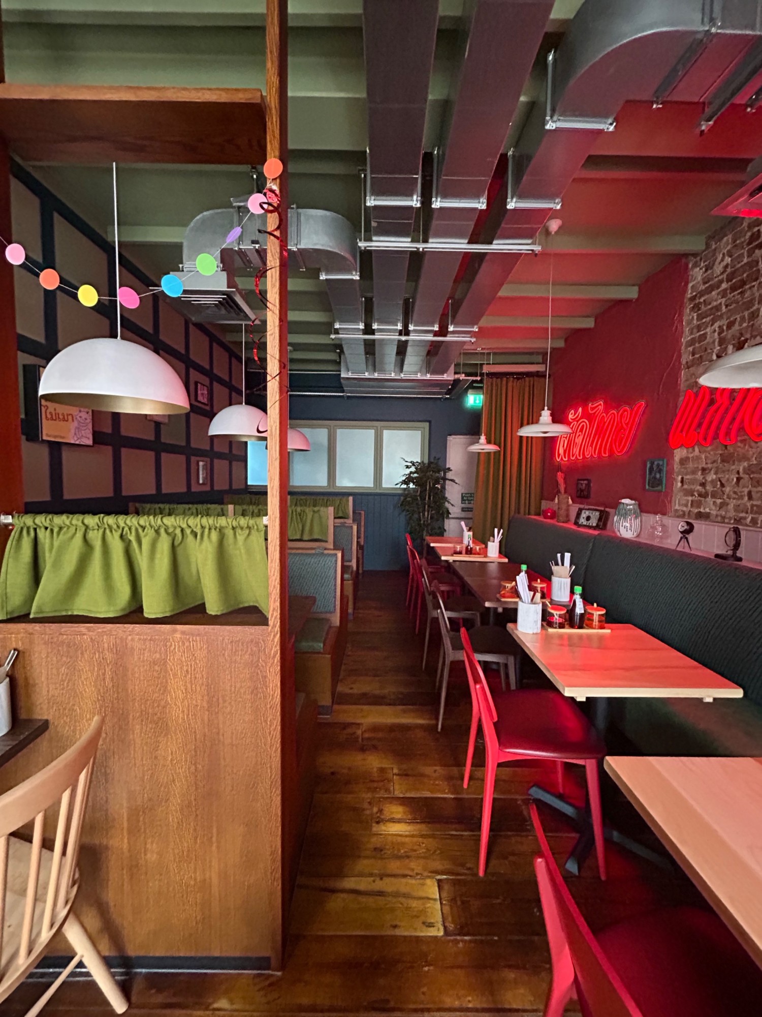 From end of divider, facing left. Half booths along right wall. Booths along left wall. Path in middle.