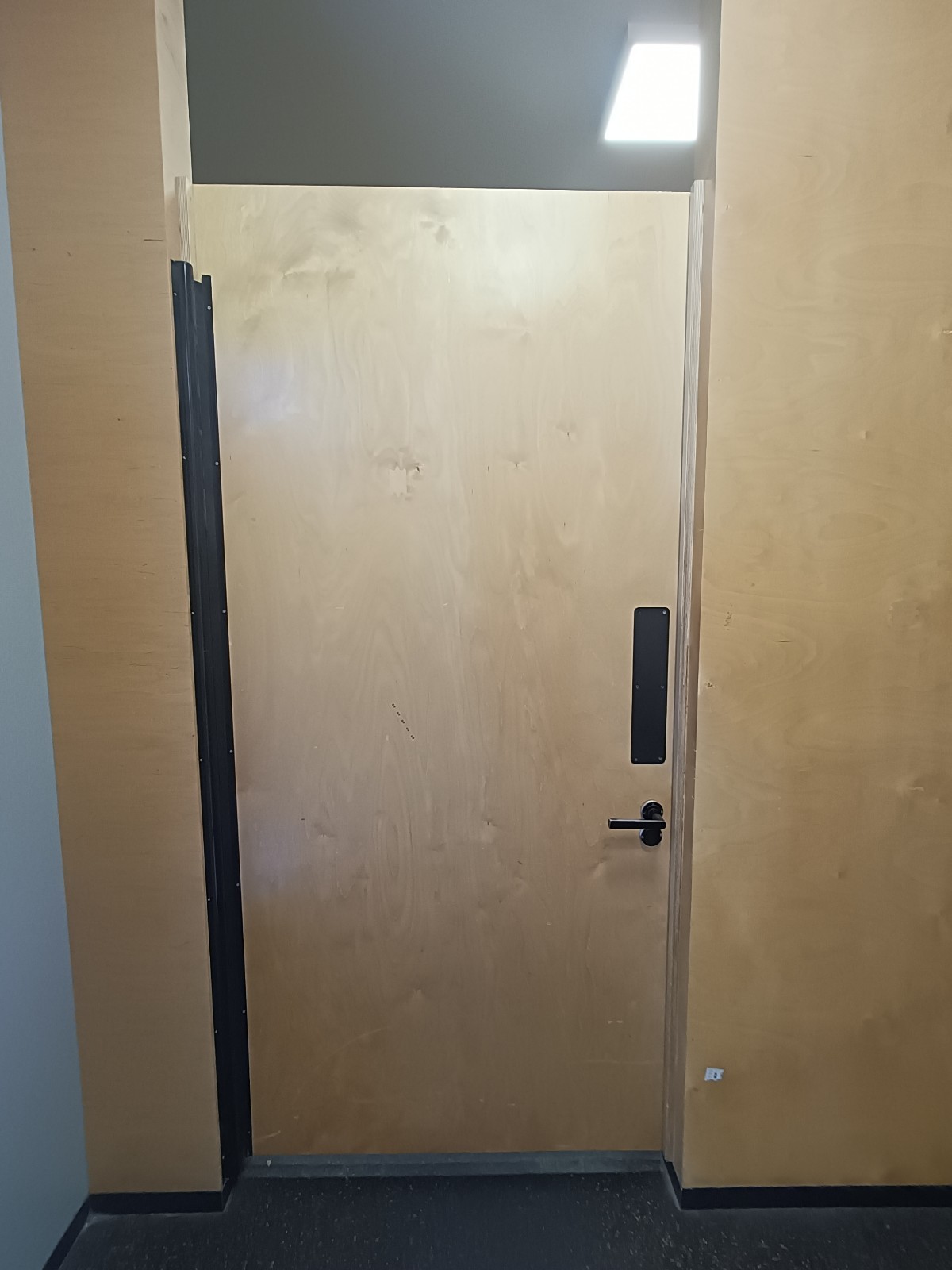 Back of fitting room door. Black, metal handle and lock on right.
