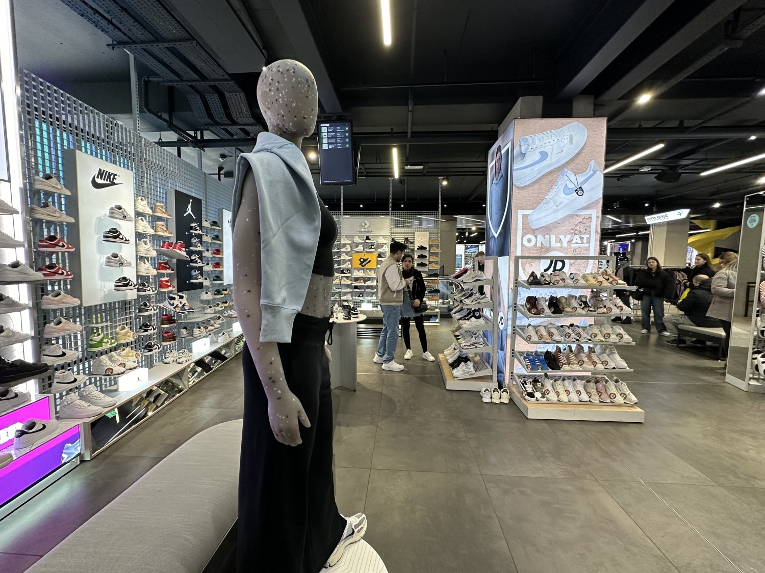 From lift looking straight. Mannequin display straight ahead, path snakes around to the right. Lift enters into the women's shoe section