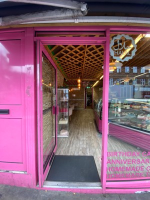Glass door, with pink doorframe. Handle on right. Push to open.