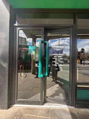 Double glass doors with black frame. Push blue vertical handles in middle to open.
