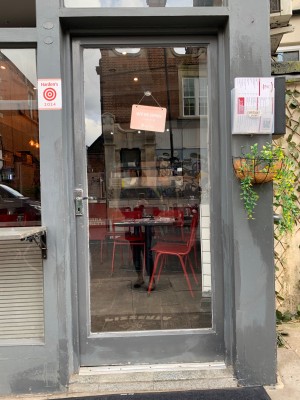 Glass door with grey wooden frame. Turn and push from silver metal handle on left of door to open.