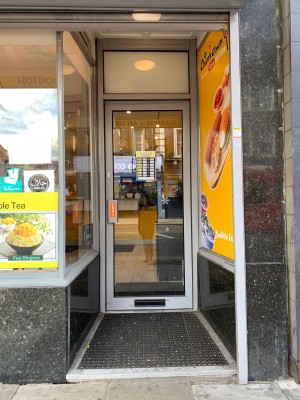 Glass door with silver metal frame. Silver metal handle on left side of door. Push handle to open.