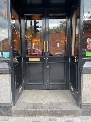Black wooden double door with glass panel. Pull vertical handles from middle to open.
