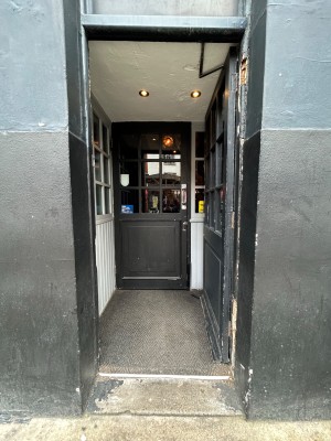 Single black wooden door with glass panels. Push from left to open.