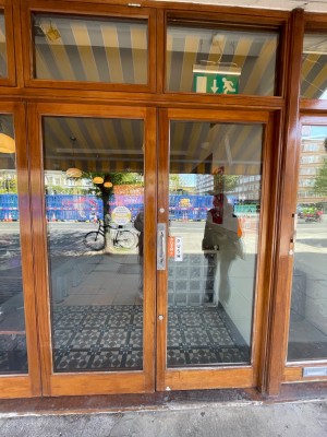Glass doors open with brown wooden frames. Push from handle in middle to open.