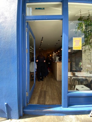 Glass door, with blue doorframe. Push on right to open.