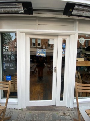 Glass door, with white doorframe. Silver handle on right. Push to open.