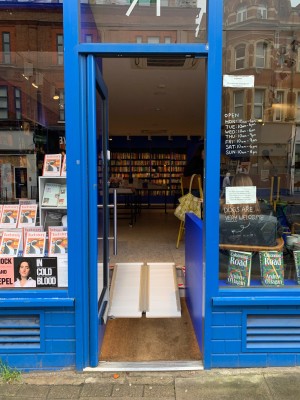 Glass door with blue wooden frame ahead. Push from right to open.