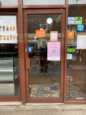 Glass door with brown frame. Push from handle on left to open.