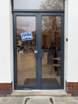 Glass doors with grey metal frames. Push from center to open.