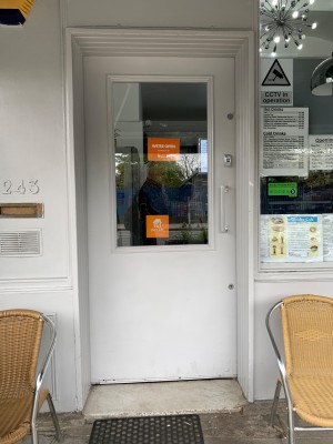 White wooden door with glass panel. Push from silver handle on right side of door to open.
