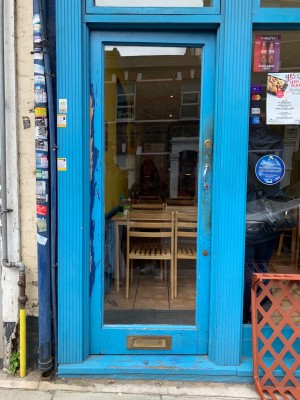 Glass door with blue wooden frames. Push from silver metal handle on right side of door to open.