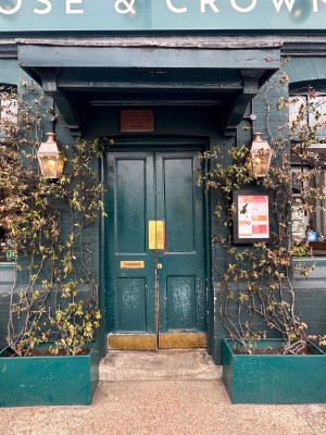 Step ahead to green wooden double doors ahead. Push golden plates from centre to open. Plants on both sides.