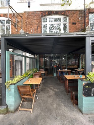 From street, facing venue. Opening at back. Outdoor seating behind. Doorway at back.