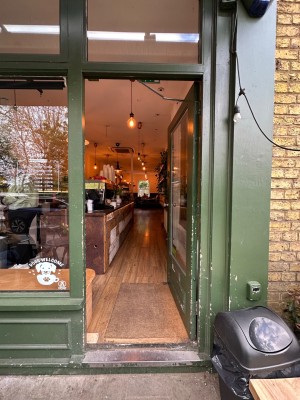 Glass single door with green doorframe. Silver handle towards left of door. Push to open.