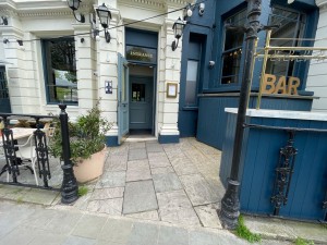 From street facing venue. Fence on left and right. Path to entrance straight inbetween. First entrance door straight in back.