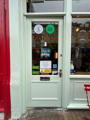 Light green and glass panelled door with silver handle to right of door. Push to open.