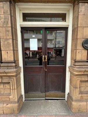 Double wood and glass panelled double doors with gold handles in centre of doors. Push to open.