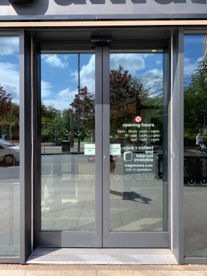 Double glass doors with grey metal frame ahead. Automatic doors slide open from centre.
