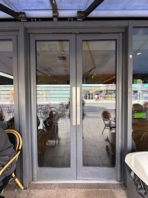 Grey framed double glass doors ahead. Push from centre to open.