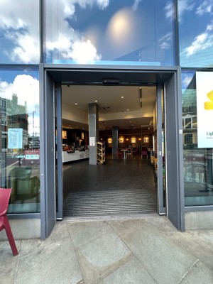 From pavement looking straight at Glass sliding double doors with grey doorframe. Slide open from centre.