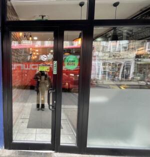 Glass door with black metal frames ahead. Push from right to open.