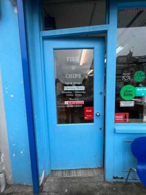 Single glass door in blue wooden frame. Silver metal handle on right. Push to open.