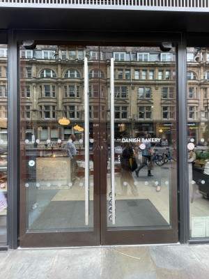 Glass doors with brown frame and silver handles in centre. Push to open.