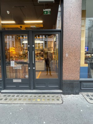 Grey wood-framed glass door. Push silver handle on left to open.