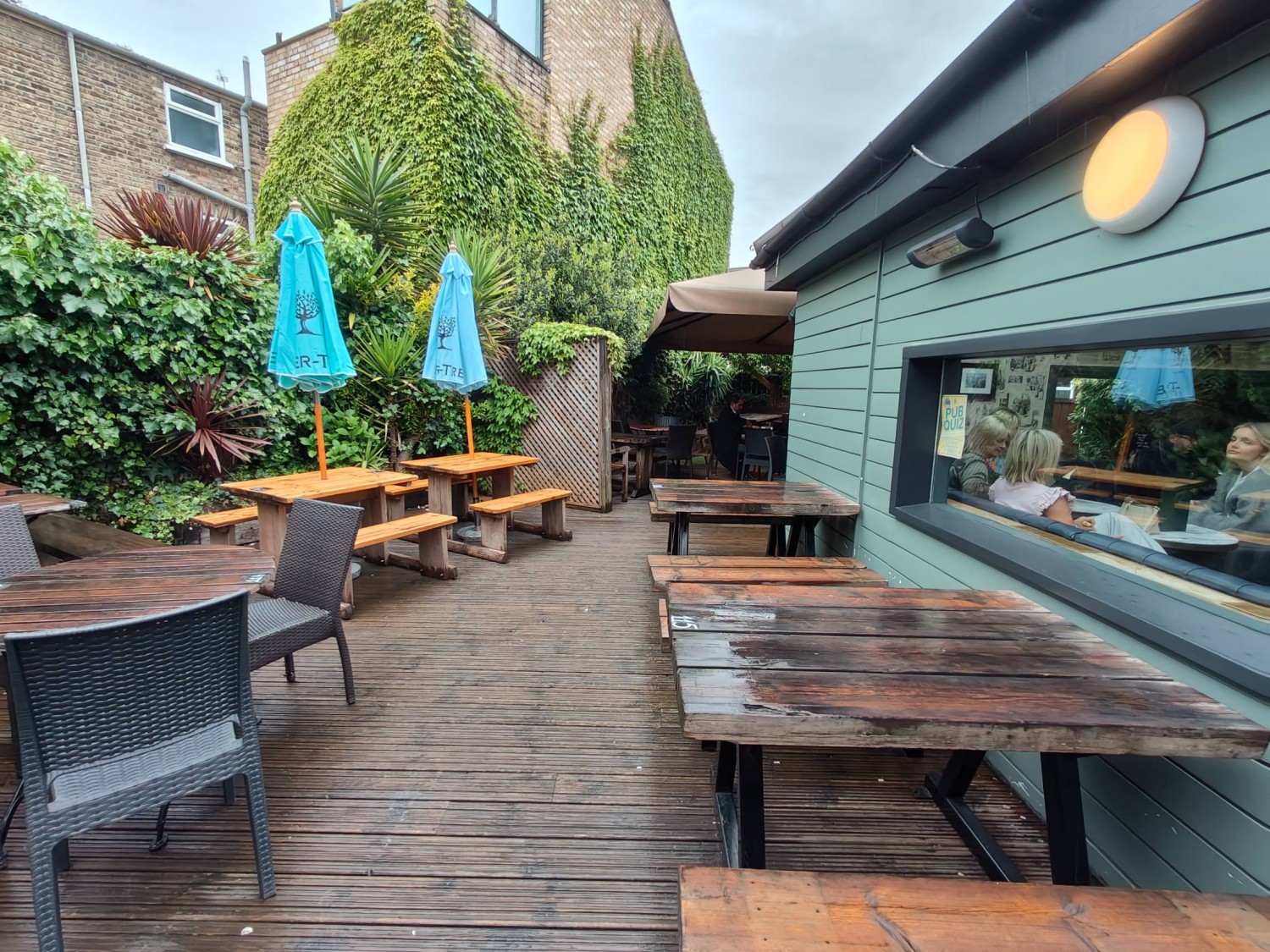 From door looking right. Picnic benches along right glass wall. Path in centre. Table & chairs on left. Picnic benches on back left.