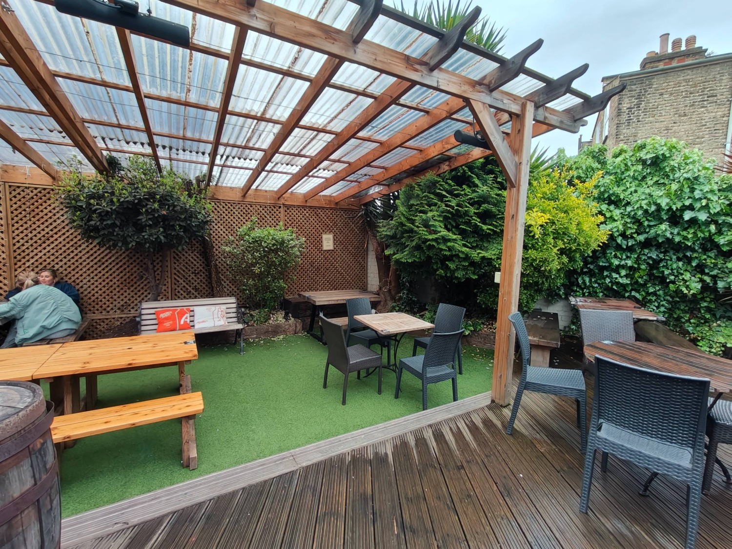 From door looking straight. Table and chairs on right and back right. Picnic benches on back left. Pole between table and chairs.