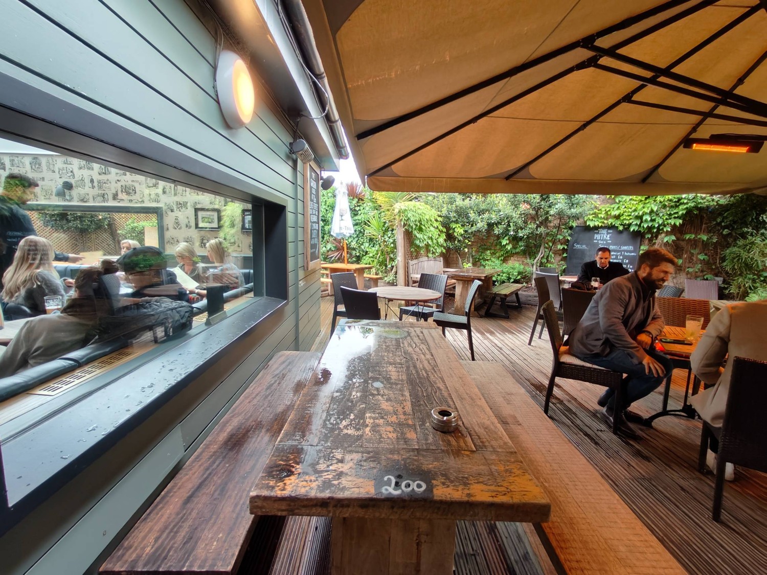 From door facing left. Picnic bench ahead. Table and chairs to the back and far right. Path on right.