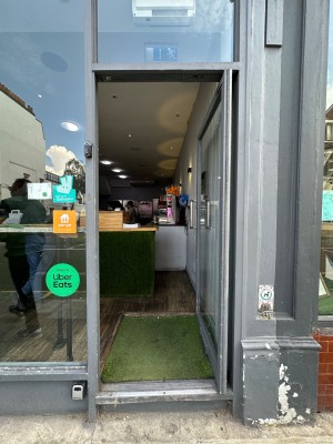 Glass door with grey doorframe. Silver handle to left of door. Push to open.
