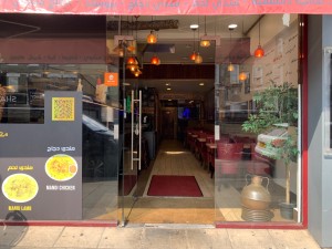 Glass door with silver metal handle on right of door. Push to open. Slope up before door.