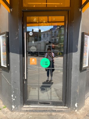 Glass door with black frame and silver metal handle on left of door. Push to open.
