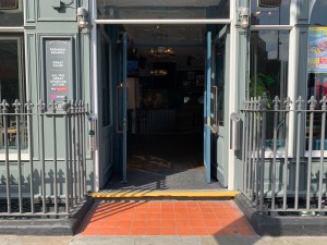 From street, facing entrance. Path straight, between fences on left and right sides and up one step to entrance doors ahead.