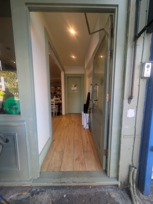 Green glass doors. Metal handle on left. Pull to open. Step at entrance.