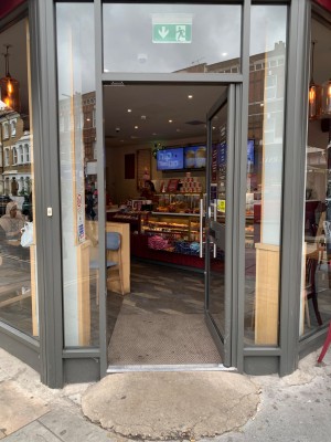 Glass door with grey metal frame ahead. Push from metal handle on left to open.