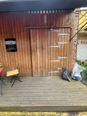 From pavement looking straight at deck area ahead followed by wooden door with gold handle on left. Pull to open.