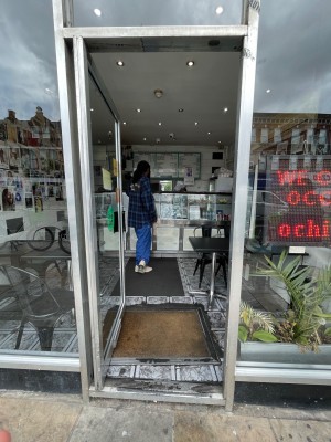 Single glass door with grey frame. Push metal handle on right to open.