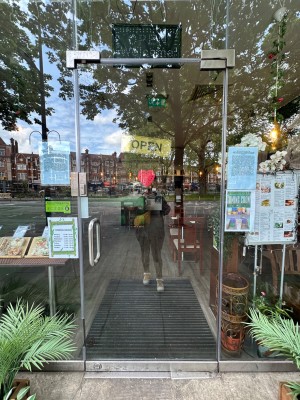 Glass door with glass frames ahead. Push handle on left to open.