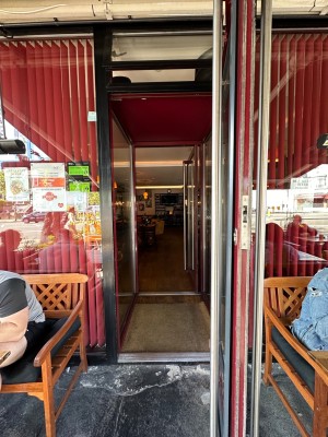 From outdoor area looking straight at glass door with vertical silver handle to left of door. Pull to open.