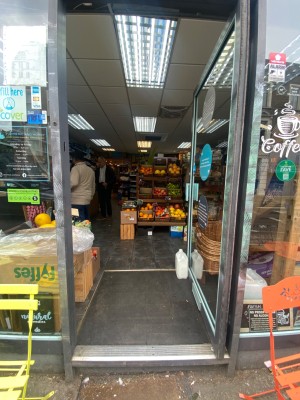 Glass door, with grey doorframe. Handle on left. Push to open.