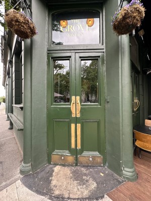 Green and glass panelled doors with gold handles in centre. Pull to open.