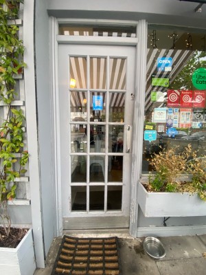 Glass door, with white wooden doorframe. Silver handle on right. Push to open.